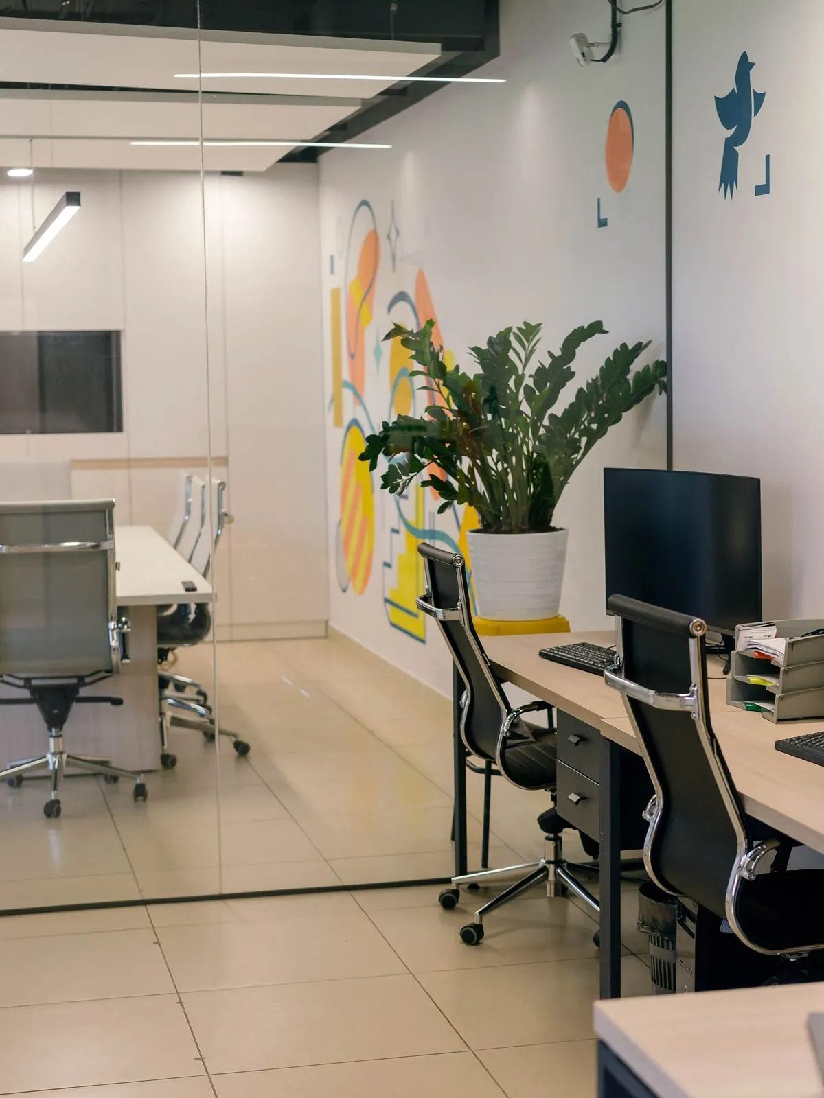 Glass-walled meeting room beside open-plan desks in an office