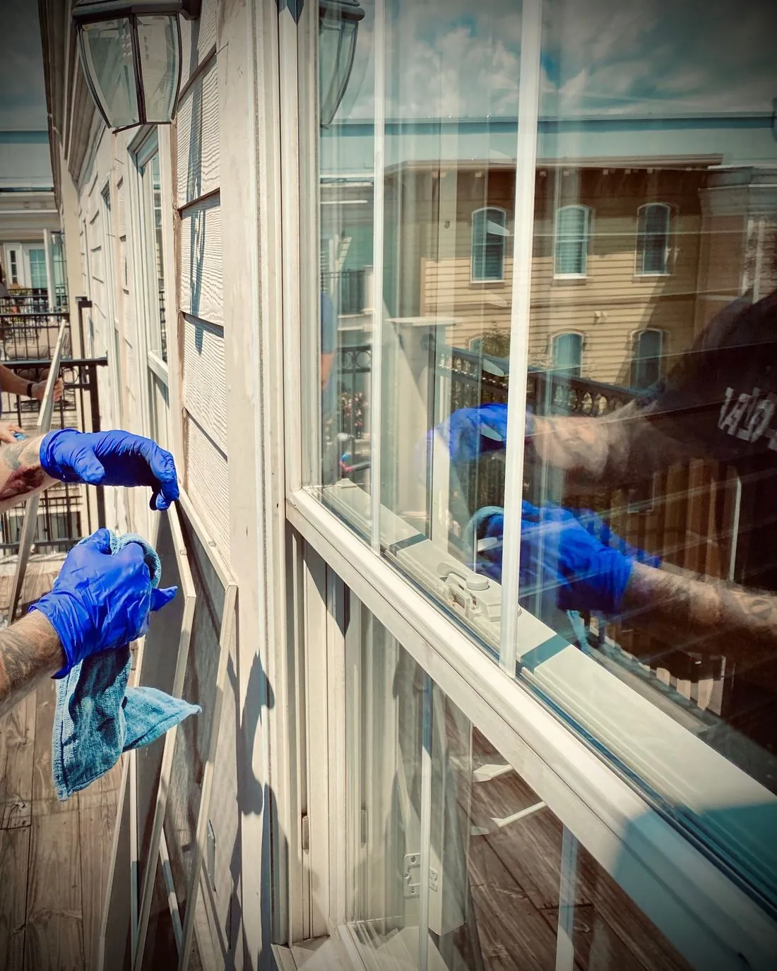 Gloved hands cleaning a storefront window from inside a shop