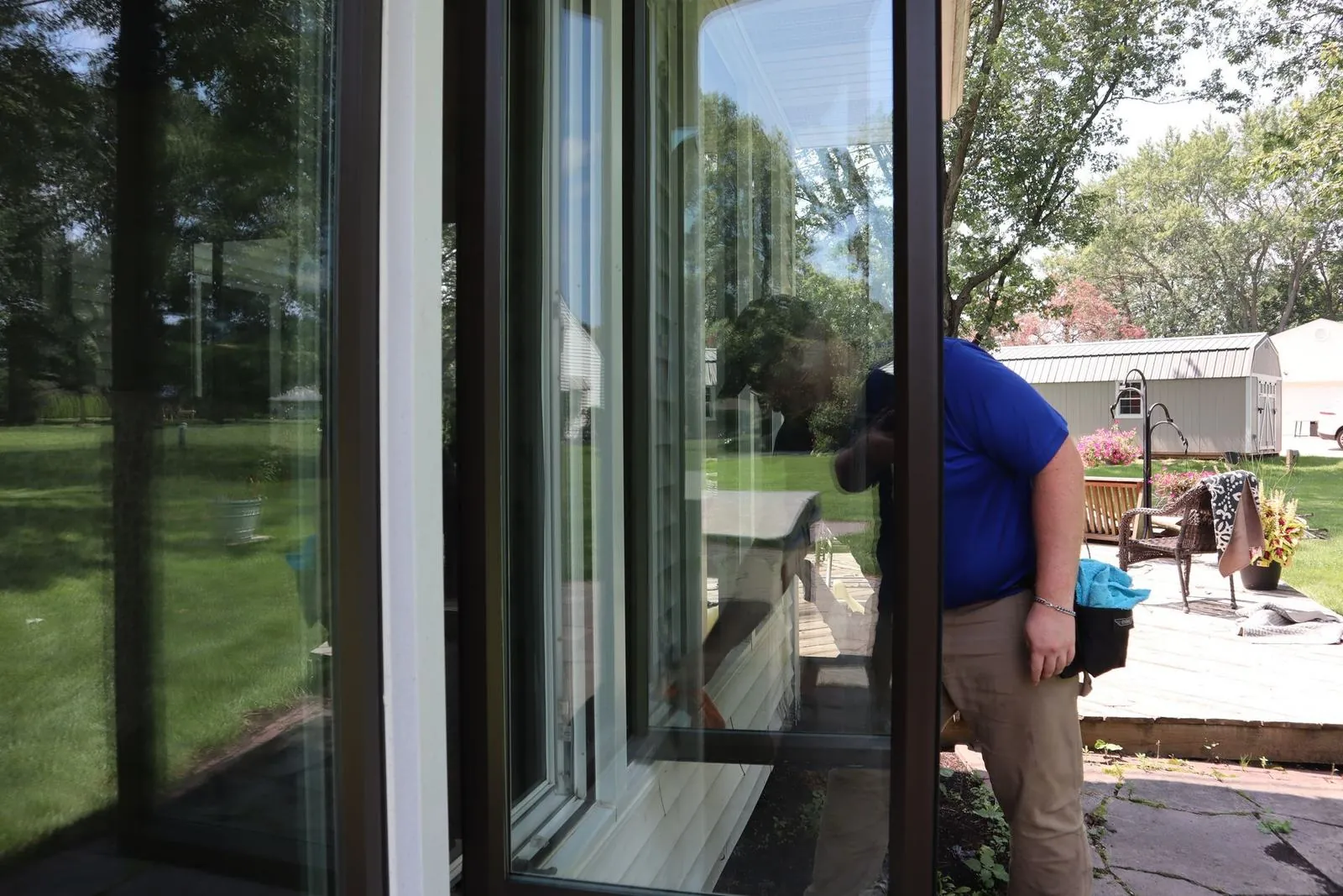 Technician cleaning glass patio doors, seen through the glass