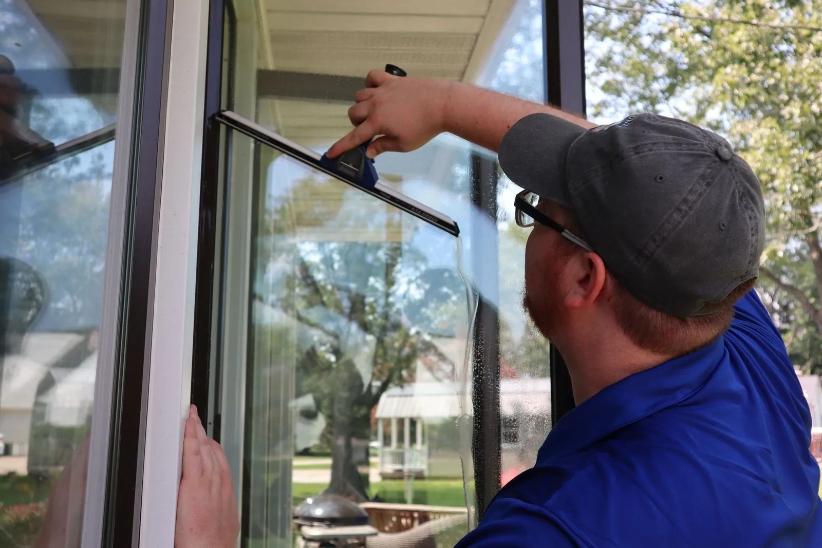 Technician using a squeegee on exterior window glass